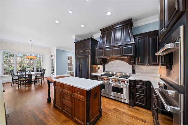 kitchen with a center island, custom range hood, decorative backsplash, decorative light fixtures, and high quality appliances