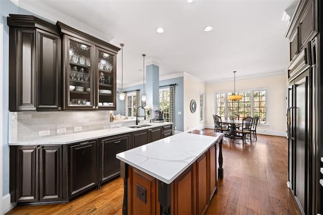 kitchen with hardwood / wood-style floors, tasteful backsplash, sink, a kitchen island, and pendant lighting