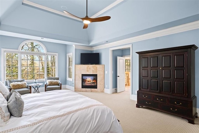 bedroom with light carpet, ceiling fan, a tray ceiling, a tile fireplace, and crown molding