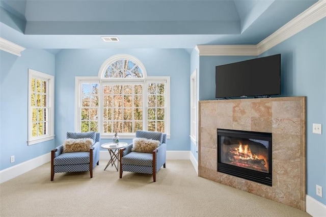 sitting room with ornamental molding, a tile fireplace, light carpet, and a raised ceiling