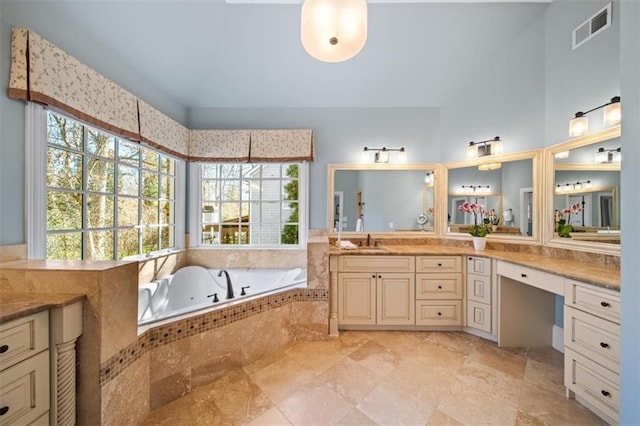 bathroom featuring tiled bath and vanity