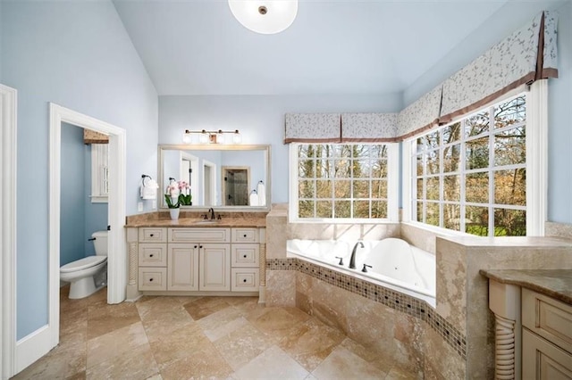 bathroom featuring tiled bath, toilet, vanity, and a healthy amount of sunlight