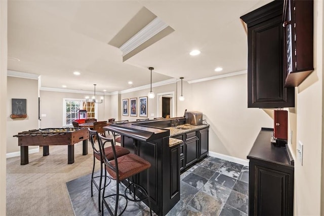 kitchen featuring kitchen peninsula, crown molding, light stone countertops, and a breakfast bar