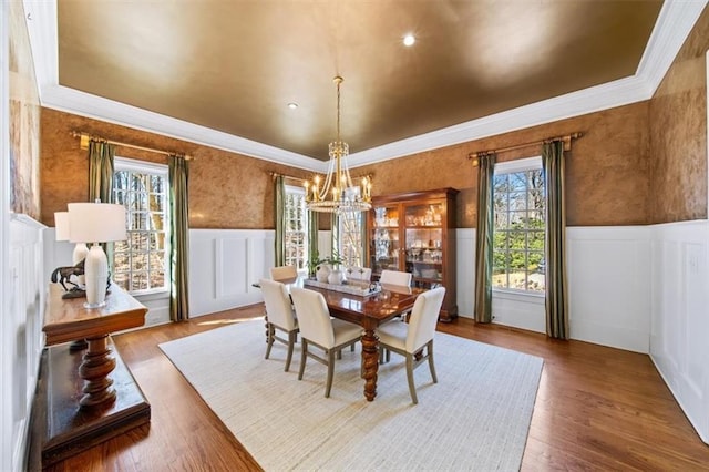 dining room featuring a notable chandelier, hardwood / wood-style flooring, a wealth of natural light, and crown molding