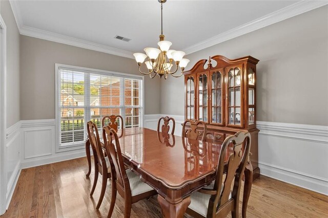 9507 Greens Mill Ct, Loganville, GA 30052 - dining room with a chandelier, wood finished floors, wainscoting, ornamental molding, and a decorative wall