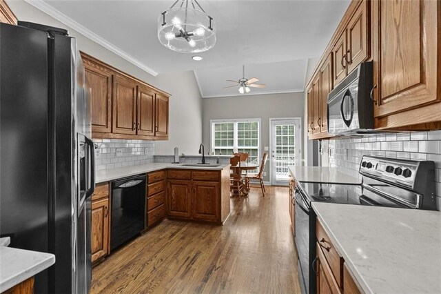 9507 Greens Mill Ct, Loganville, GA 30052 - kitchen with black appliances, a peninsula, dark wood-type flooring, brown cabinets, and a sink