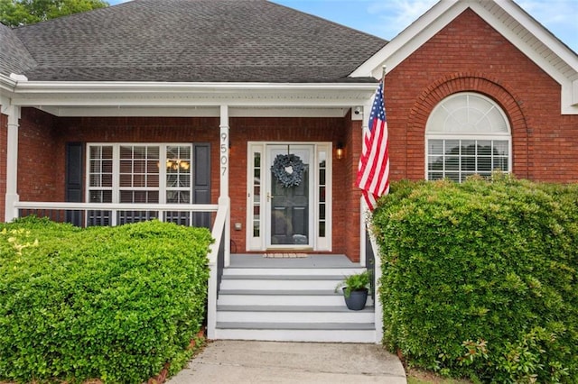 9507 Greens Mill Ct, Loganville, GA 30052 - view of exterior entry with brick siding, a shingled roof, and covered porch