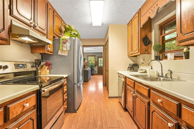 kitchen with appliances with stainless steel finishes, sink, a textured ceiling, and light hardwood / wood-style floors