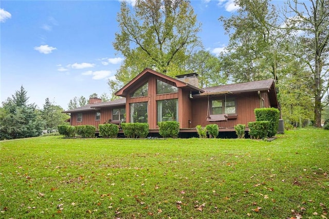 back of property with central AC and a lawn