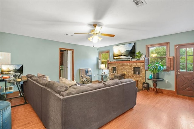 living room with a fireplace, light hardwood / wood-style flooring, and ceiling fan