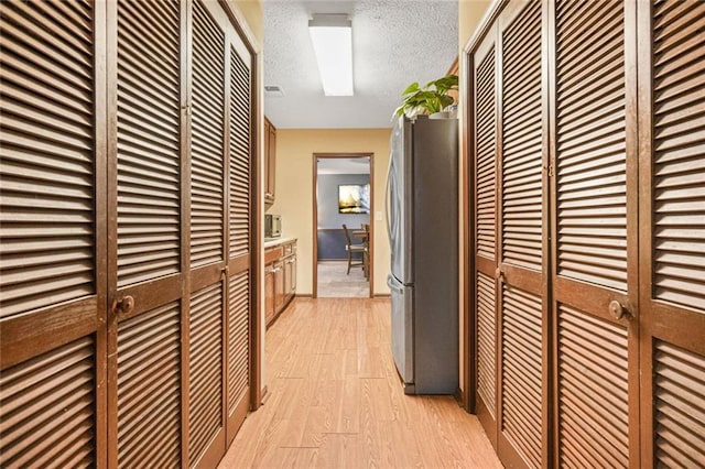 corridor with light hardwood / wood-style flooring and a textured ceiling