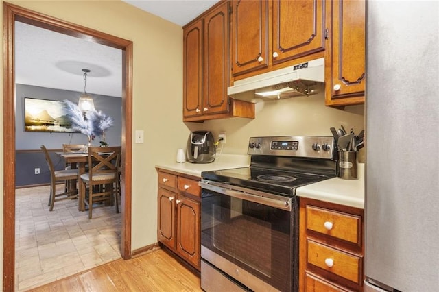 kitchen with decorative light fixtures, stainless steel appliances, and light hardwood / wood-style floors