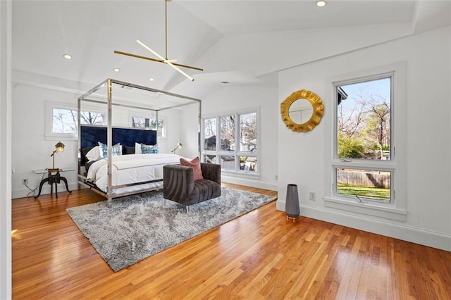 bedroom featuring multiple windows, lofted ceiling, baseboards, and hardwood / wood-style floors