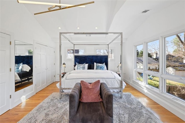 bedroom featuring visible vents, light wood-style flooring, and lofted ceiling