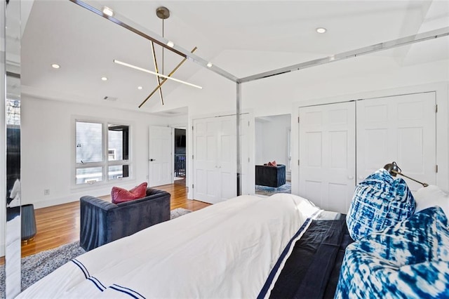 bedroom with lofted ceiling, recessed lighting, wood finished floors, and multiple closets