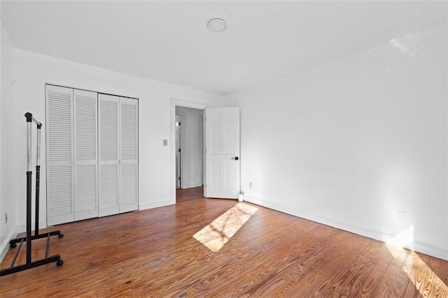 unfurnished bedroom with wood finished floors, a closet, and baseboards