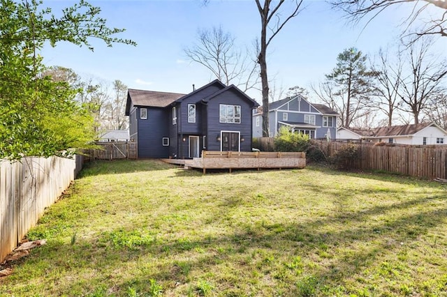 rear view of house featuring a deck, a lawn, and a fenced backyard