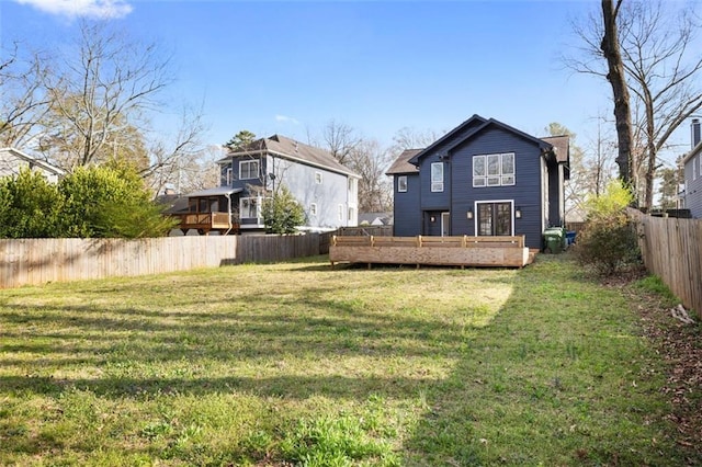 back of house featuring a deck, a yard, a fenced backyard, and a chimney