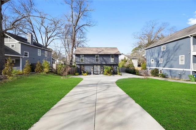 rear view of house with concrete driveway, a yard, and a residential view