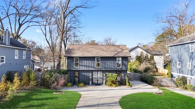 view of front facade featuring concrete driveway, a front yard, and fence