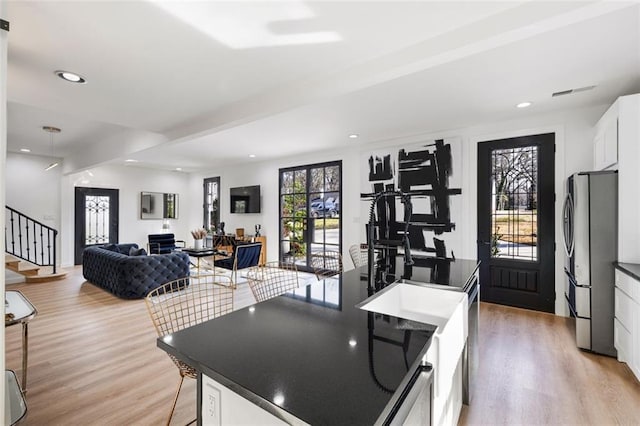 kitchen with dark countertops, white cabinets, light wood finished floors, and freestanding refrigerator