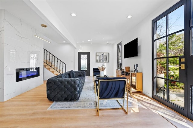 living room with stairs, light wood finished floors, recessed lighting, and a high end fireplace