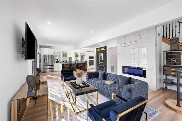 living room featuring light wood finished floors, visible vents, recessed lighting, and a fireplace