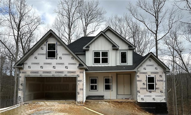 unfinished property featuring a garage, driveway, and board and batten siding