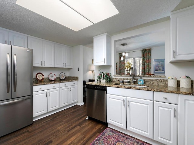 kitchen featuring white cabinetry, sink, dark stone counters, stainless steel appliances, and dark wood-type flooring