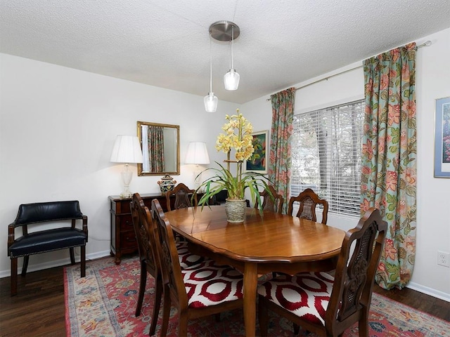 dining space with dark wood-type flooring and a textured ceiling