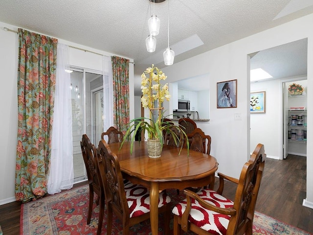 dining space with dark wood-type flooring and a textured ceiling