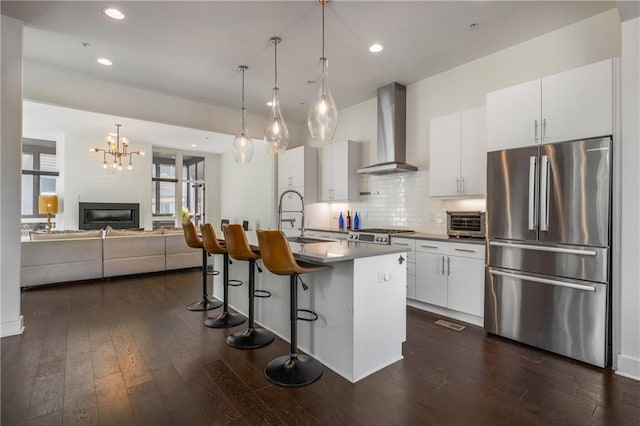 307 Cedar Dust Dr, Decatur, GA 30030 - kitchen featuring freestanding refrigerator, wall chimney range hood, dark wood-style floors, a breakfast bar, and recessed lighting