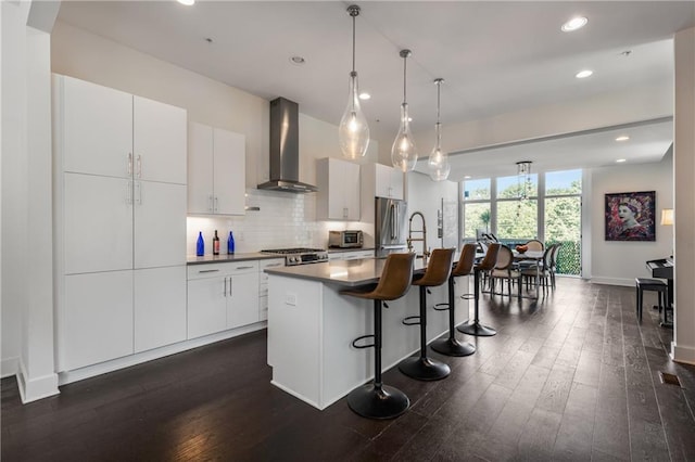307 Cedar Dust Dr, Decatur, GA 30030 - kitchen featuring wall chimney range hood, freestanding refrigerator, a kitchen bar, dark wood-style floors, and a kitchen island with sink