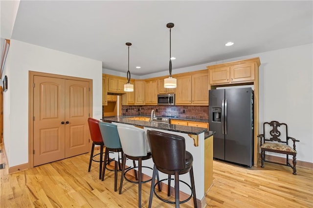 6324 Chesla Dr, Gainesville, GA 30506 - kitchen with appliances with stainless steel finishes, light wood-style floors, tasteful backsplash, a kitchen island with sink, and a kitchen breakfast bar