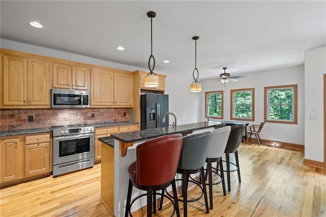 6324 Chesla Dr, Gainesville, GA 30506 - kitchen featuring appliances with stainless steel finishes, a kitchen breakfast bar, tasteful backsplash, a kitchen island with sink, and light wood finished floors