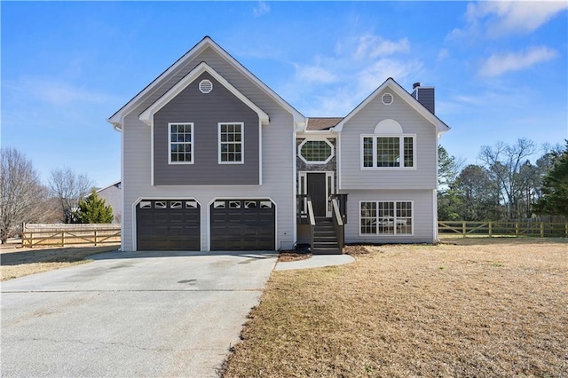 bi-level home with a garage and a front lawn