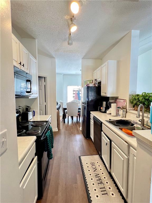 1731 Pryor Rd SW Unit 307, Atlanta, GA 30315 - kitchen featuring black appliances, a textured ceiling, light countertops, white cabinetry, and dark wood-style flooring