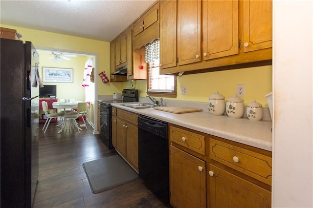 kitchen featuring black appliances, under cabinet range hood, brown cabinets, and a sink