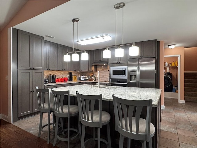 714 Arden Dr, Winder, GA 30680 - kitchen featuring appliances with stainless steel finishes, a sink, backsplash, a kitchen island with sink, and a breakfast bar
