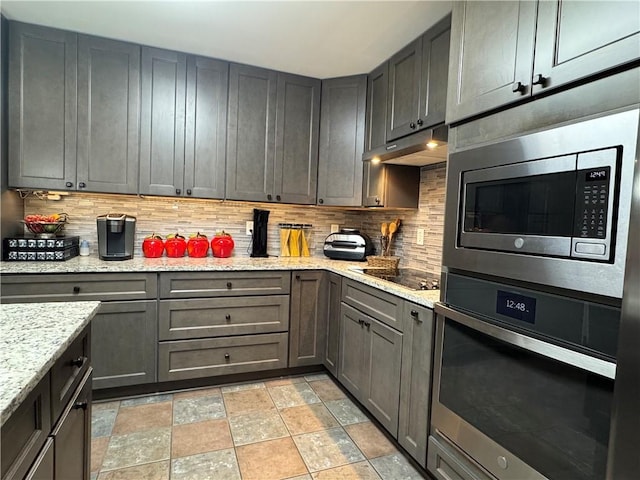 714 Arden Dr, Winder, GA 30680 - kitchen featuring appliances with stainless steel finishes, tasteful backsplash, stone finish floors, under cabinet range hood, and light stone counters