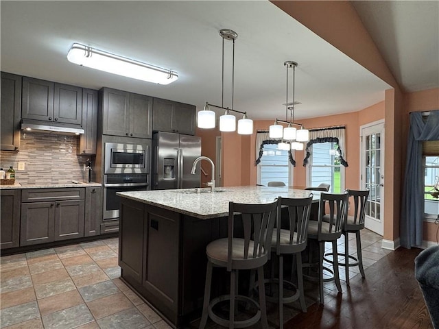 714 Arden Dr, Winder, GA 30680 - kitchen with appliances with stainless steel finishes, a sink, under cabinet range hood, a kitchen bar, and backsplash