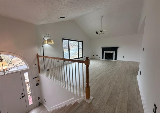 entryway featuring a high end fireplace, a wealth of natural light, a textured ceiling, and hardwood / wood-style flooring