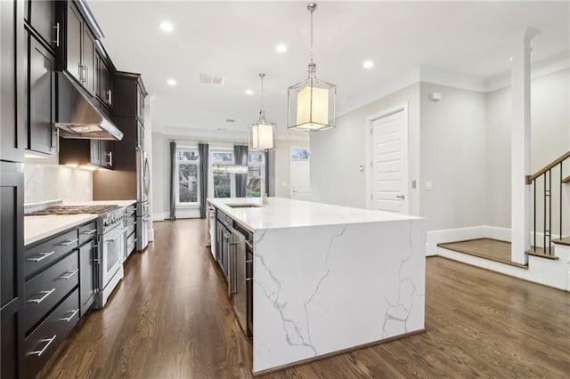 kitchen featuring a large island, a sink, appliances with stainless steel finishes, crown molding, and dark wood-style flooring