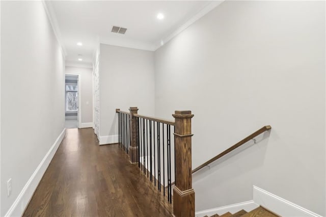 hall featuring visible vents, baseboards, ornamental molding, an upstairs landing, and wood finished floors