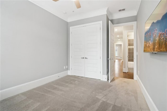 unfurnished bedroom with baseboards, visible vents, carpet floors, ornamental molding, and a closet