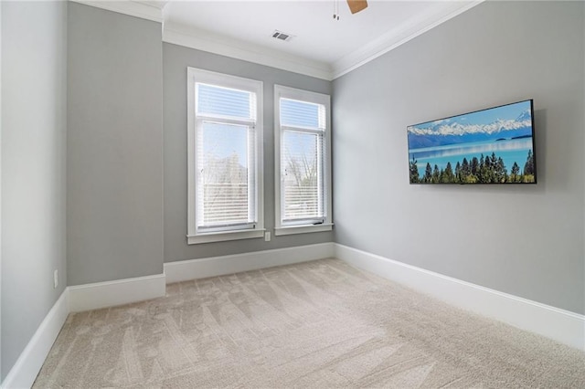 carpeted empty room featuring ceiling fan, baseboards, visible vents, and ornamental molding