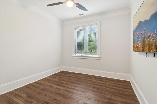 empty room featuring dark wood-style floors, visible vents, crown molding, and baseboards