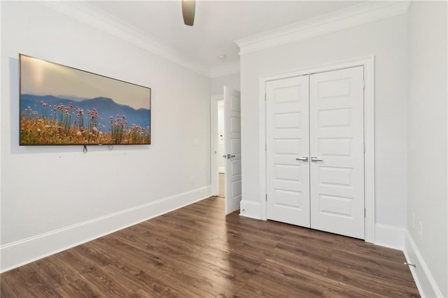 unfurnished bedroom featuring a closet, baseboards, dark wood-type flooring, and ornamental molding