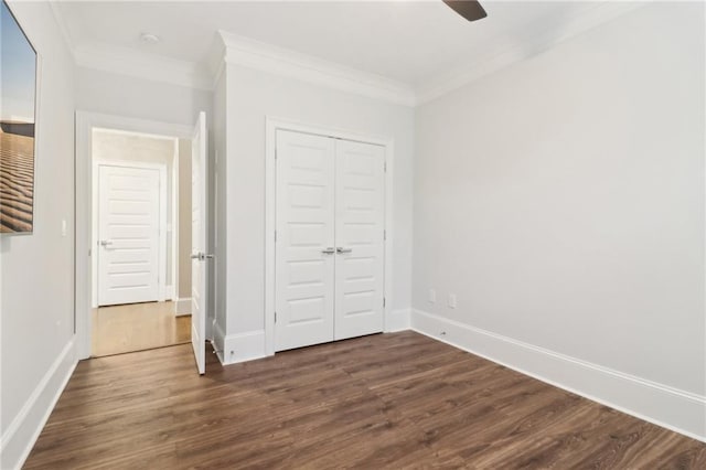 unfurnished bedroom featuring a closet, baseboards, dark wood-style floors, and ornamental molding