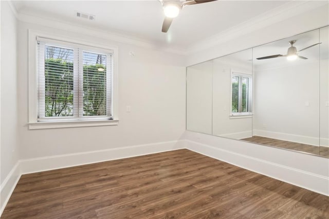 unfurnished room featuring visible vents, baseboards, wood finished floors, and crown molding